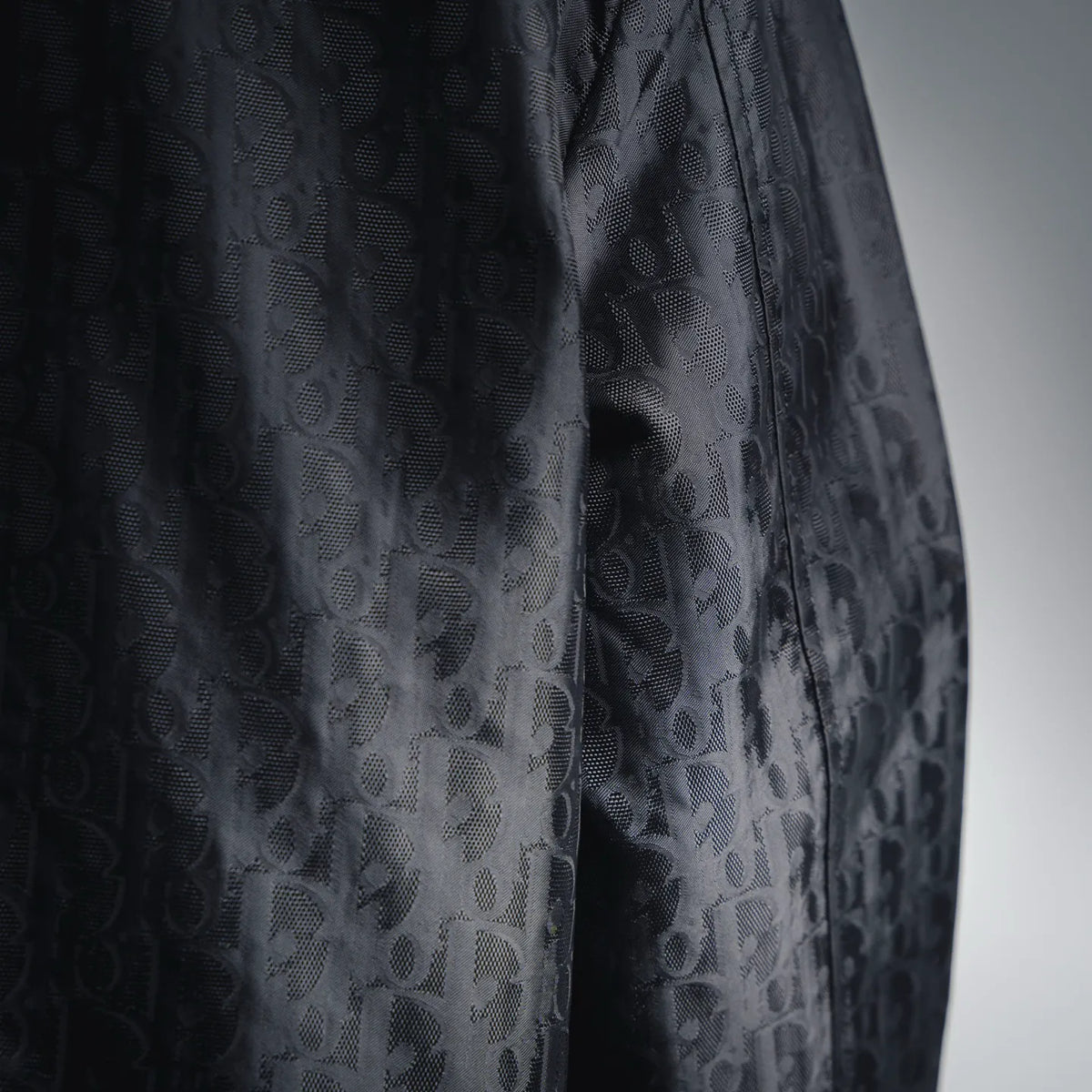 Close-up of dark monogram patterned coat fabric in allover repeating print