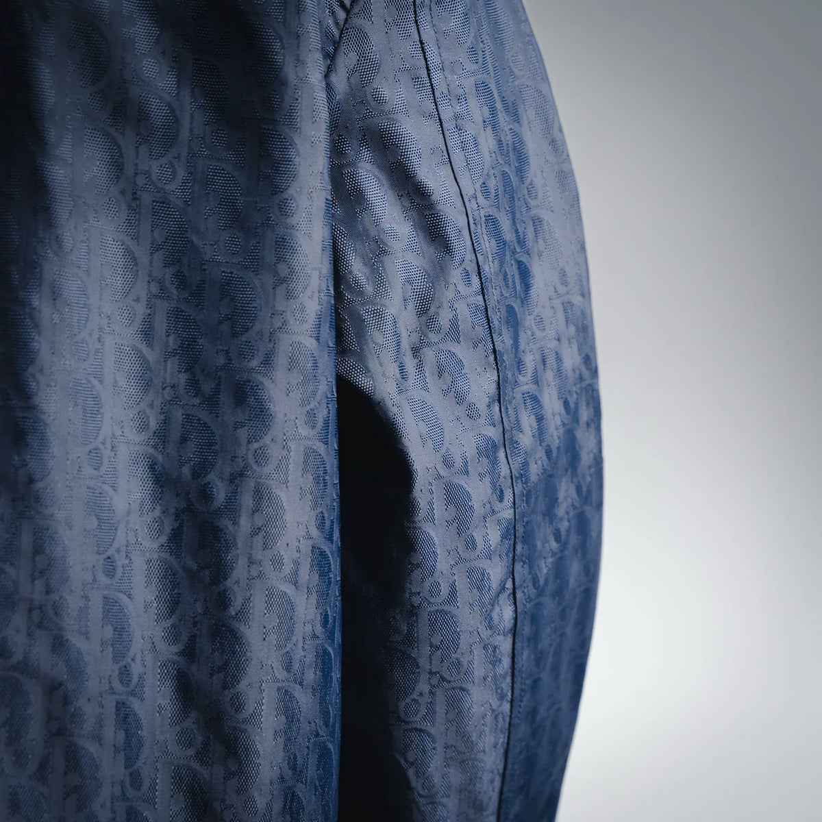 Dior dark blue coat fabric with repeating logo pattern and vertical seam
