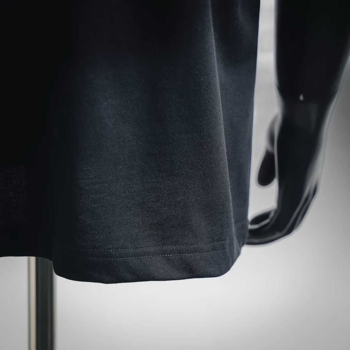 Black T-shirt hem with stitched edge and smooth knit fabric