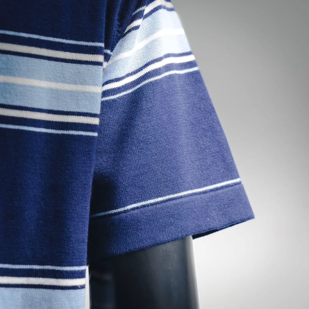Blue polo sleeve hem with white and light-blue horizontal stripe bands