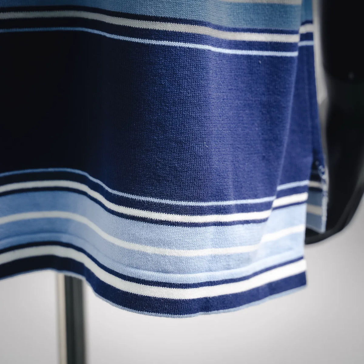 Blue polo hem with white and light-blue striped band detail