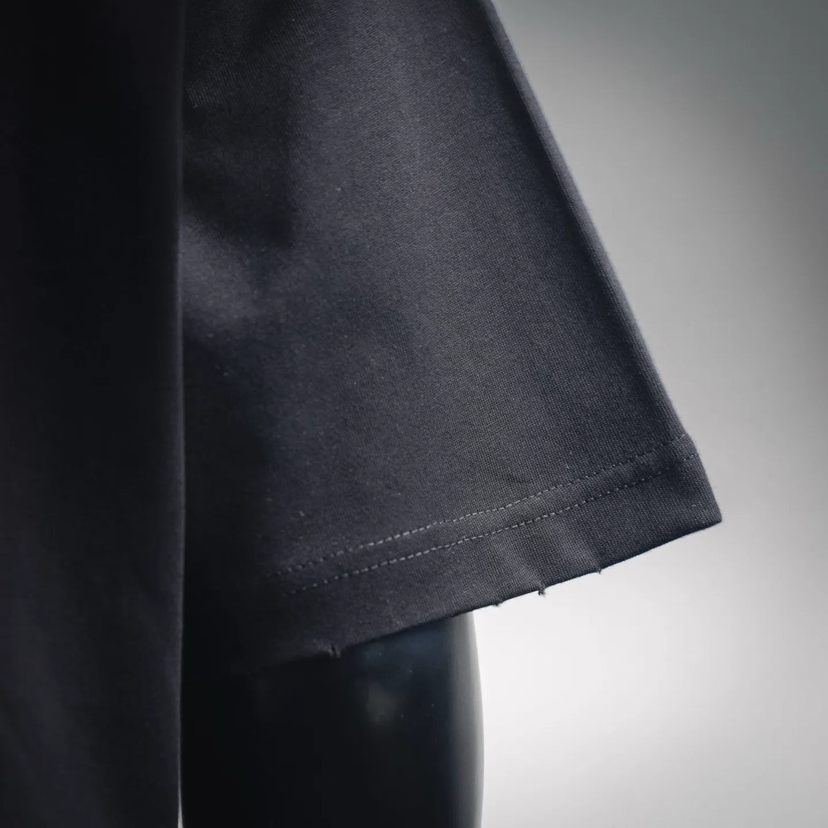 Black T-shirt sleeve hem with visible stitching and folded edge