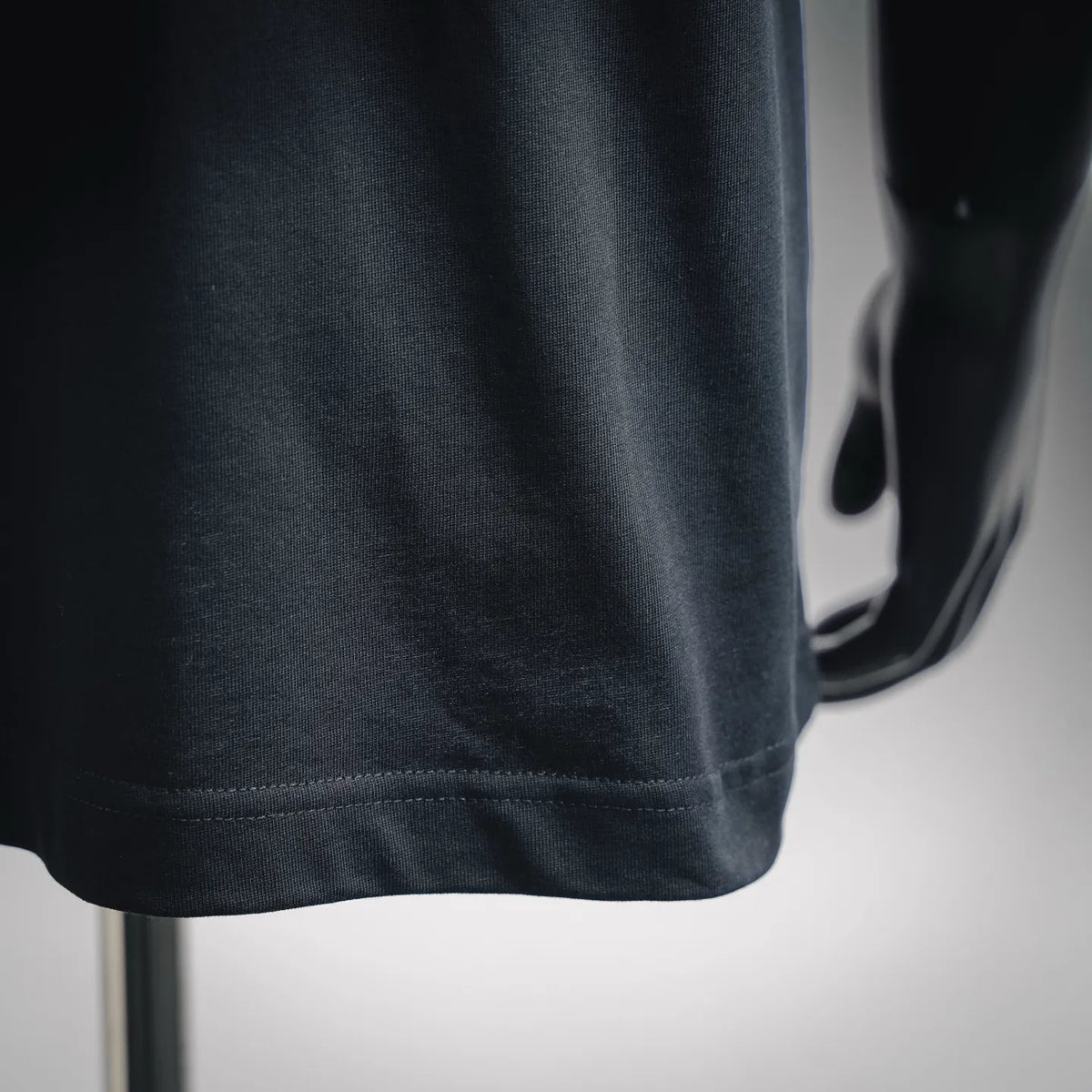 Dark T-shirt hem close-up with stitched bottom and smooth jersey knit