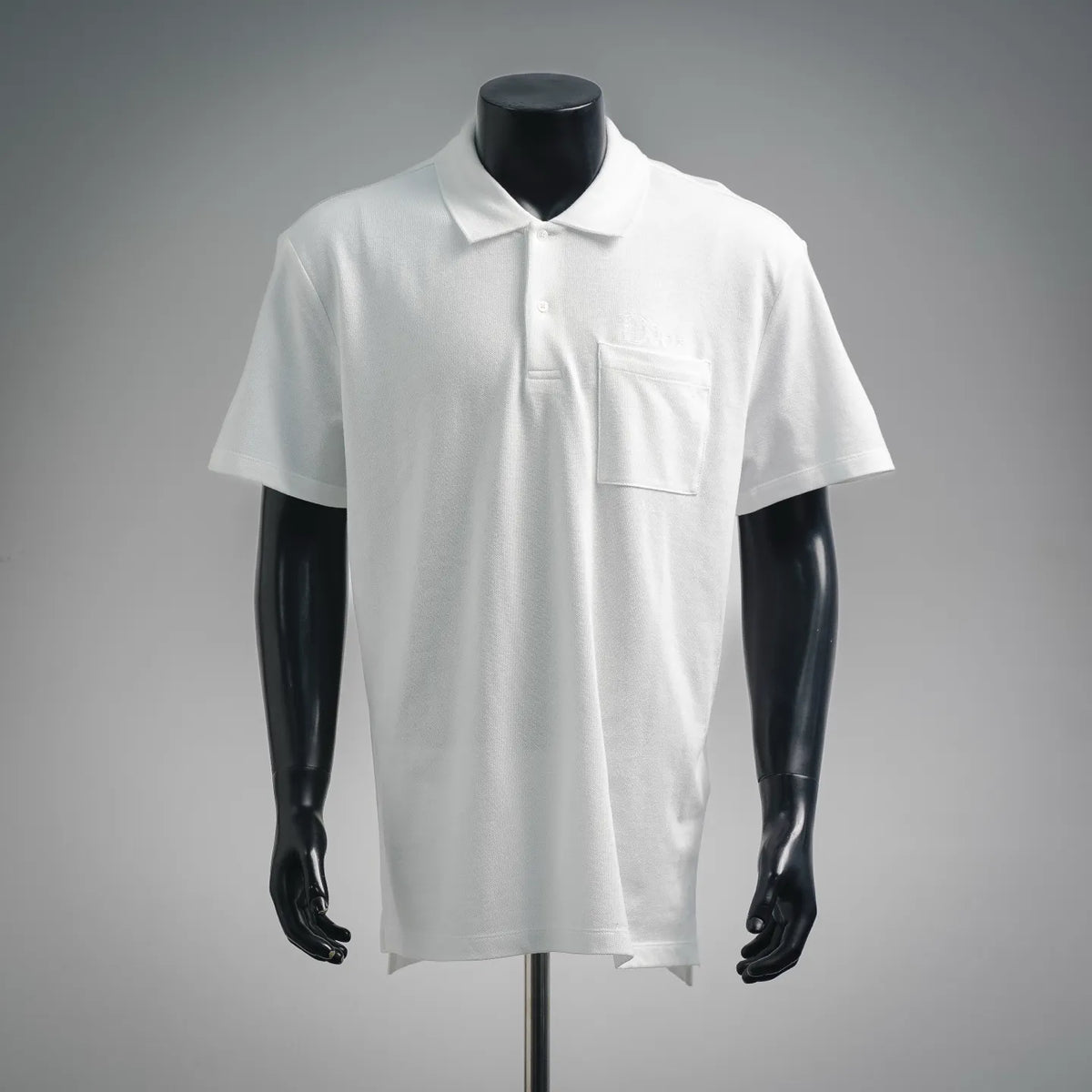 White Dior polo shirt with short sleeves, collar, and front chest pocket.