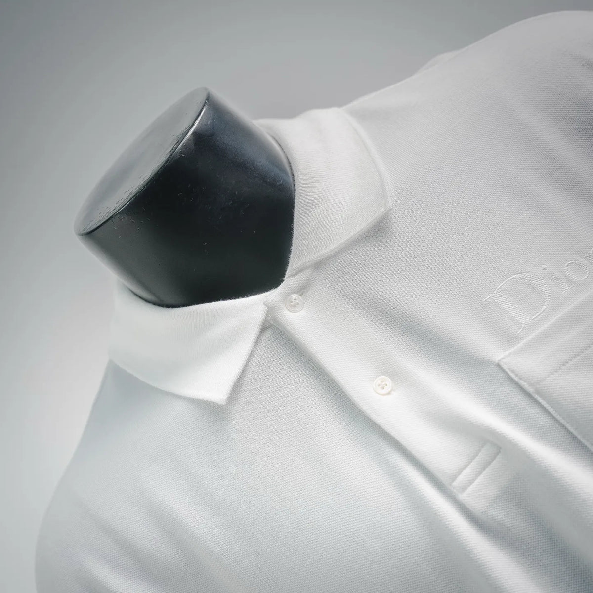White polo shirt button placket close-up with small front buttons.