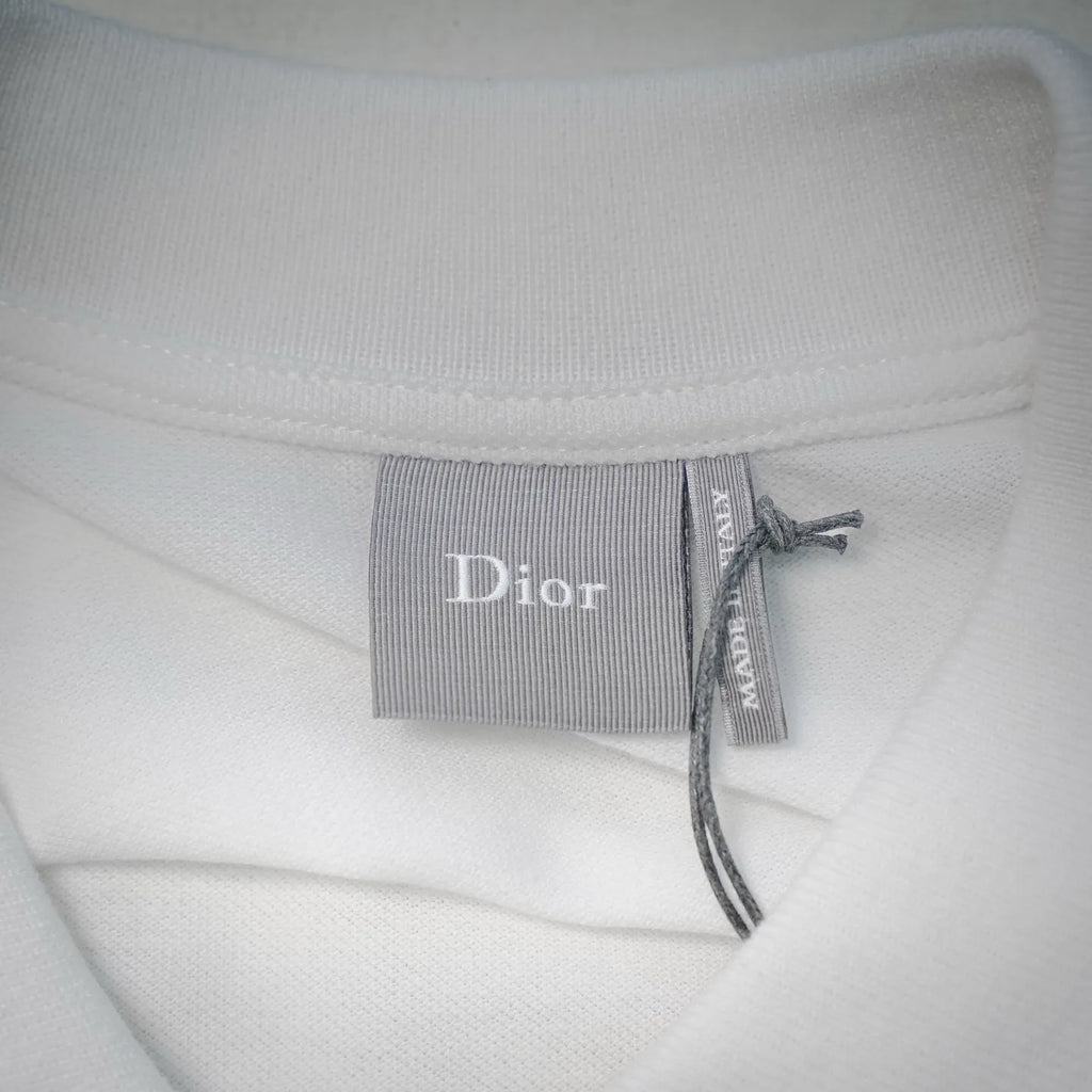 White Dior polo shirt neck label reading “Dior” with ribbon tie.