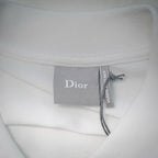 White Dior polo shirt neck label reading “Dior” with ribbon tie.