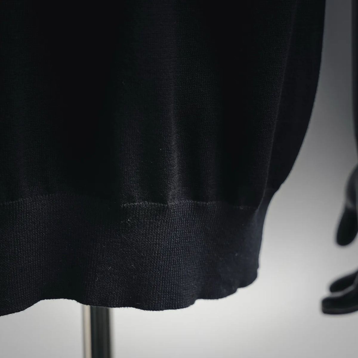 Black polo shirt hem with ribbed knit finish; close-up of bottom edge