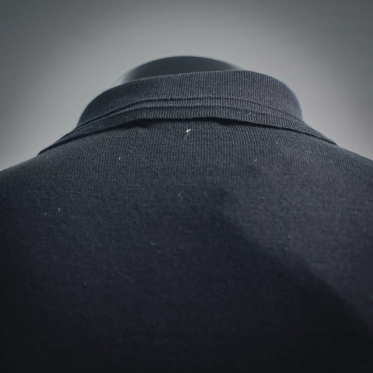 Black polo collar and shoulder area with ribbed trim; close-up