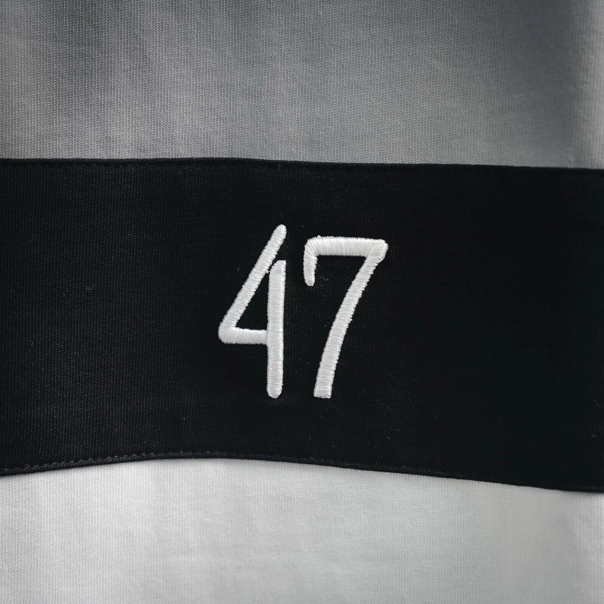 Close-up of embroidered “47” on a black stripe graphic