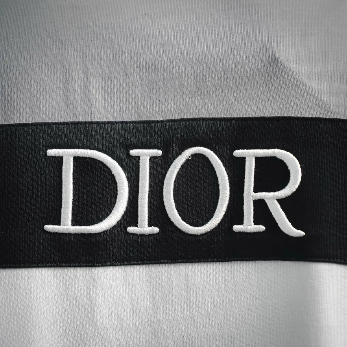 Close-up of embroidered “DIOR” on a black stripe panel