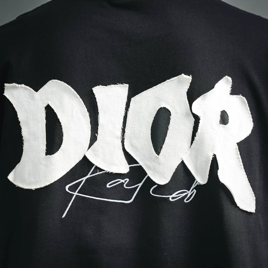 Close-up of white Dior logo embroidery on black short-sleeve T-shirt