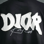 Close-up of white Dior logo embroidery on black short-sleeve T-shirt