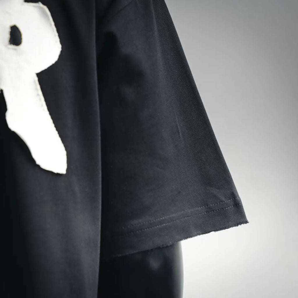 Black short-sleeve T-shirt side seam and hem detail with white logo partial