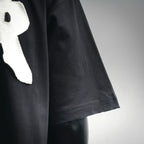 Black short-sleeve T-shirt side seam and hem detail with white logo partial