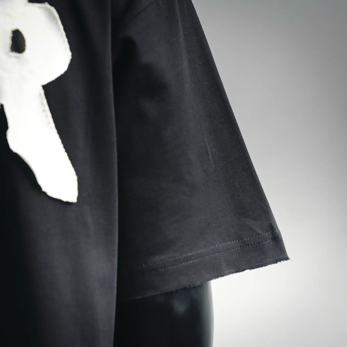 Black short-sleeve T-shirt side seam and hem detail with white logo partial