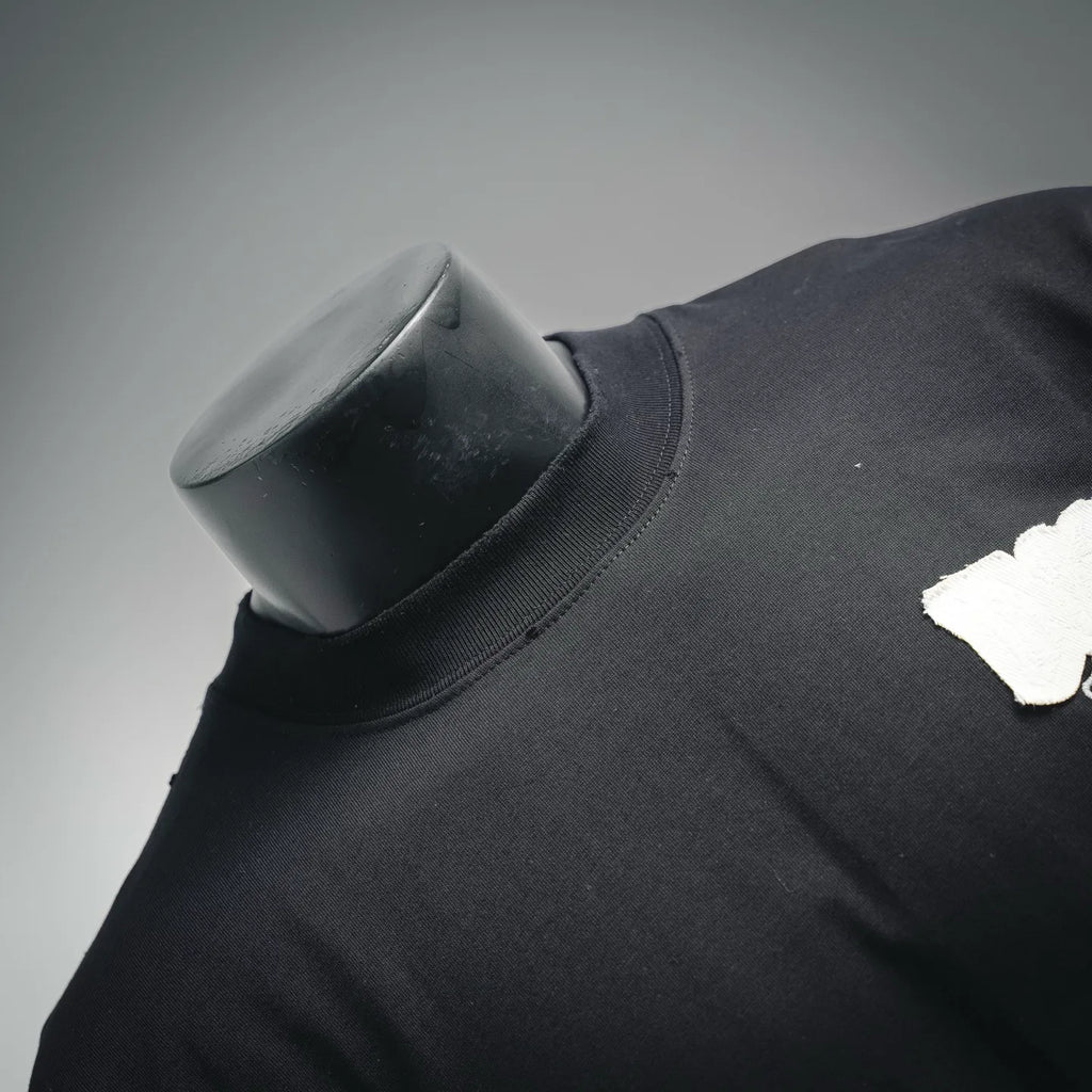 Black short-sleeve T-shirt neckline and shoulder seam with small white logo patch