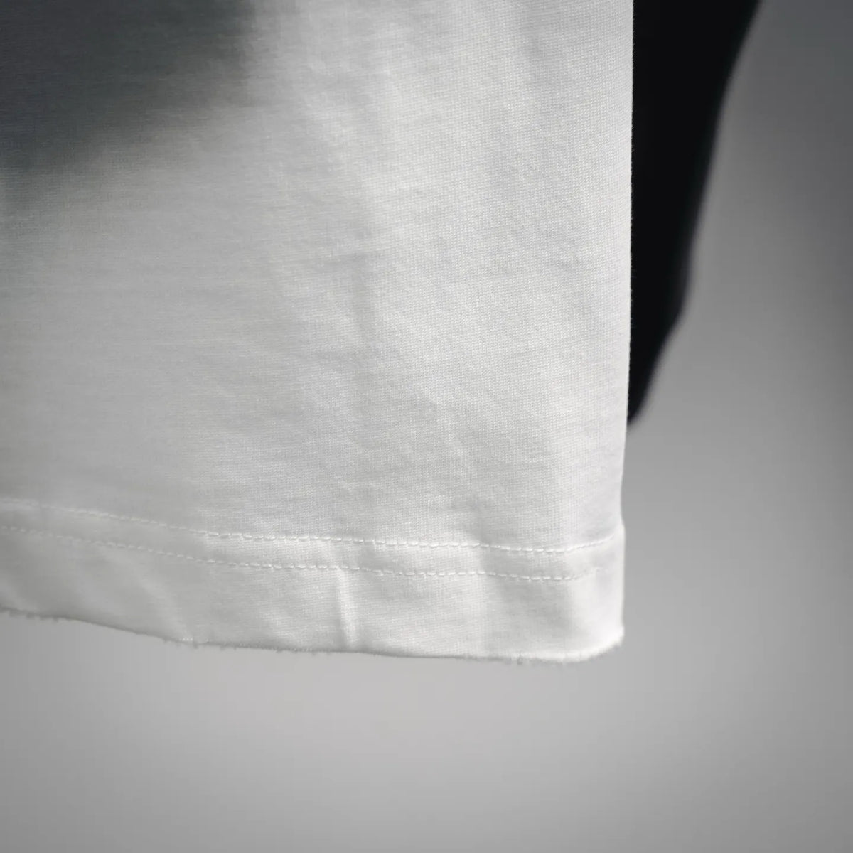 White Dior T-shirt hem close-up with visible stitching and clean seam finish