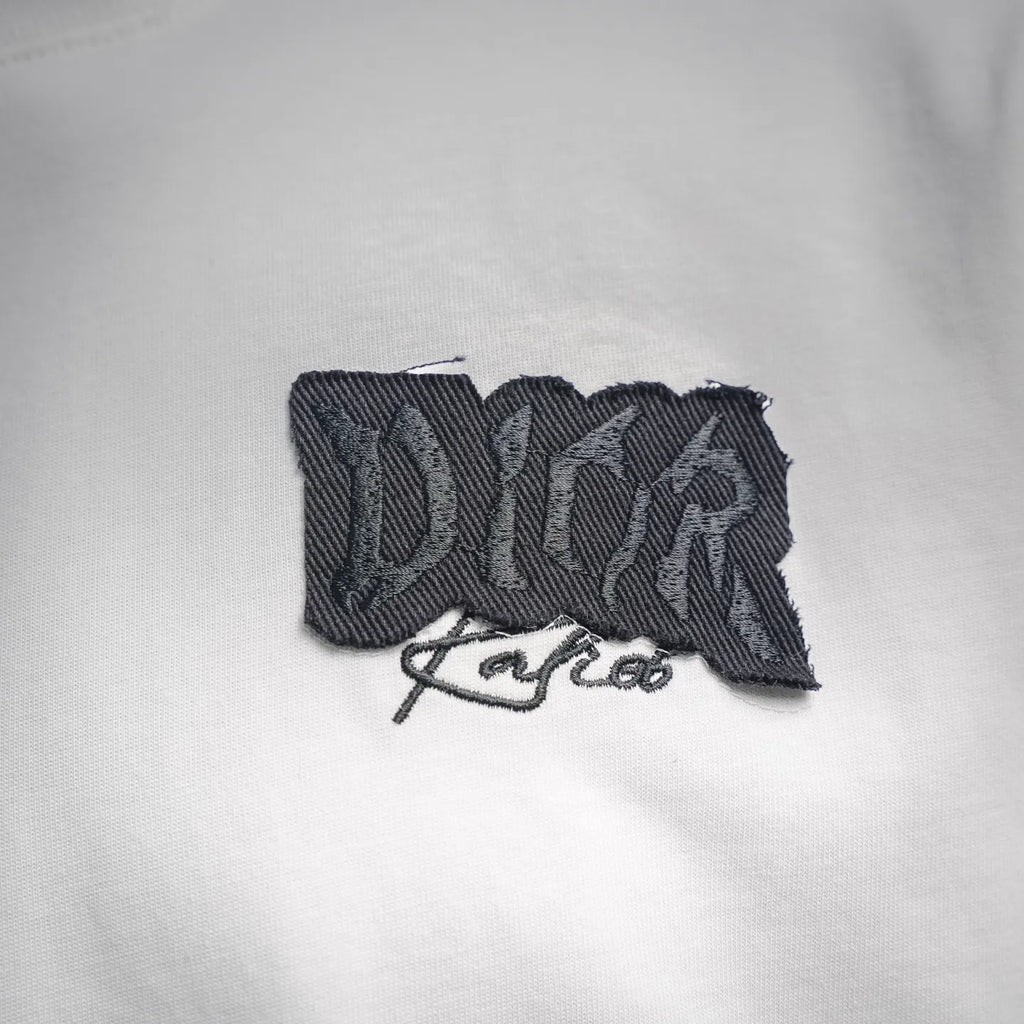 Black Dior embroidered logo patch on a white Dior T-shirt chest