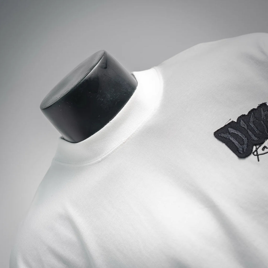 White Dior T-shirt neckline and shoulder close-up with small black logo