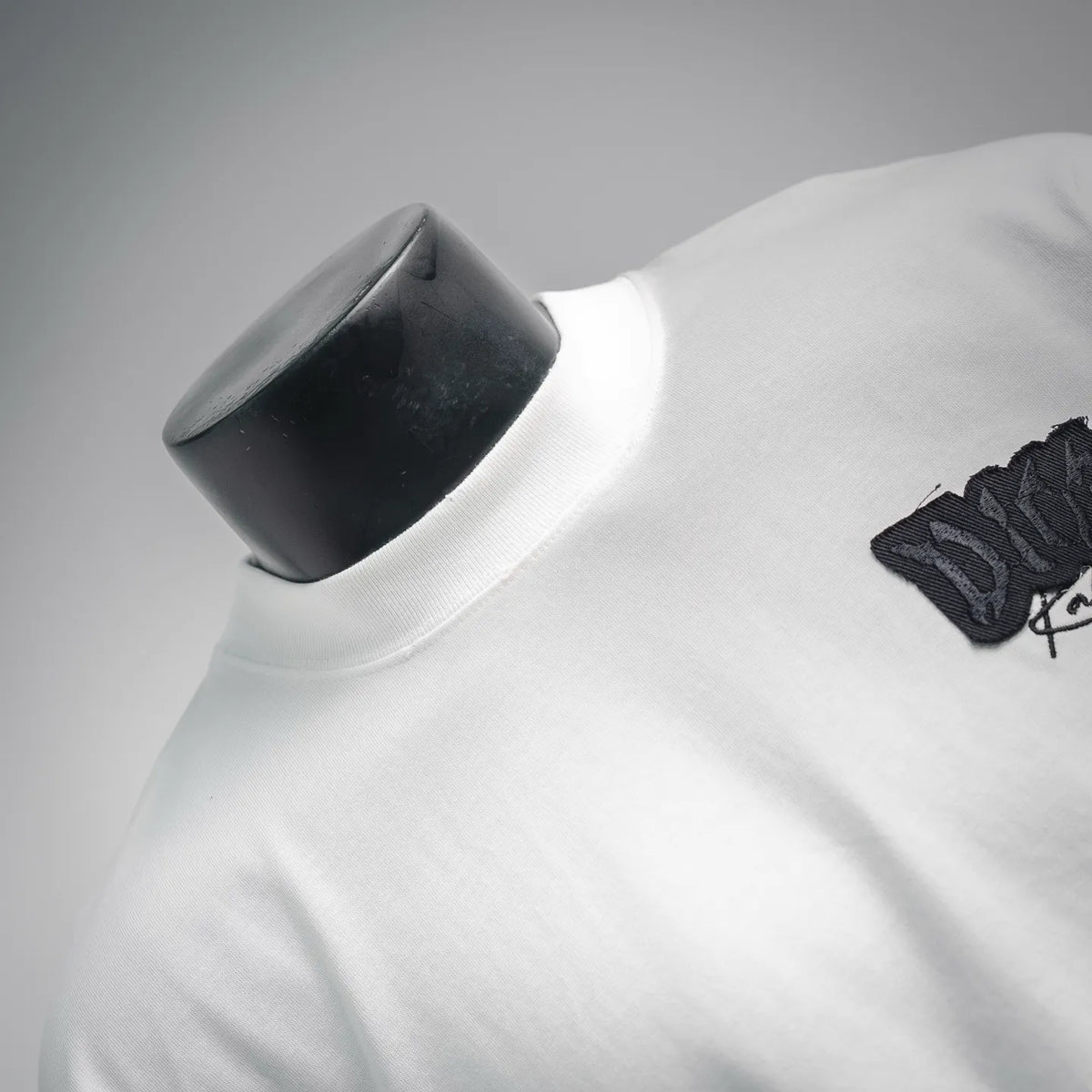 White Dior T-shirt neckline and shoulder close-up with small black logo