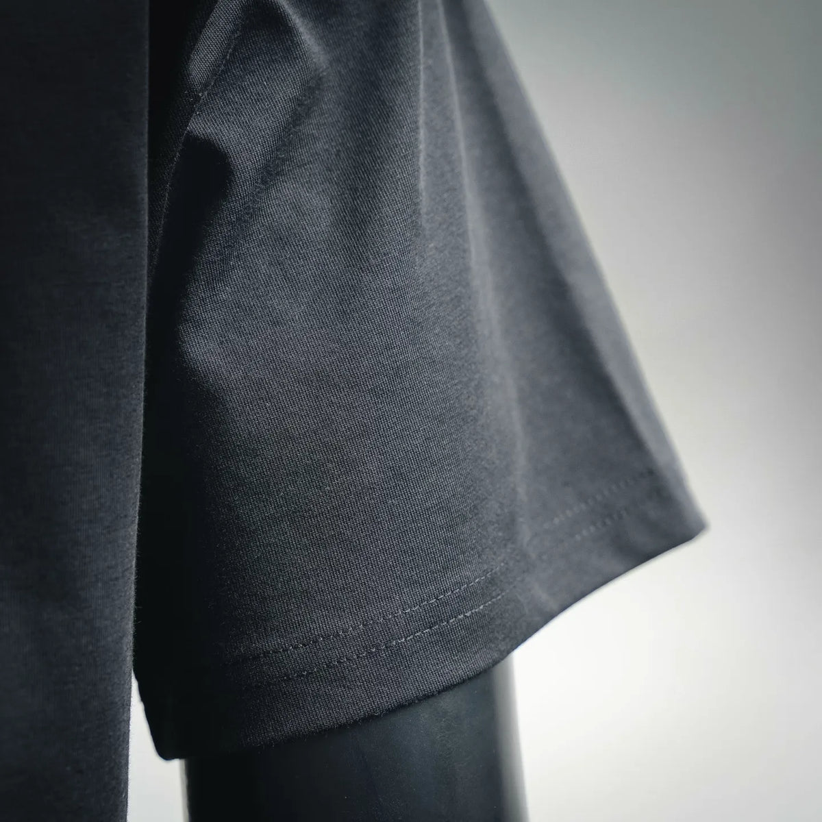 Dior crew-neck T-shirt sleeve close-up, dark fabric with stitched cuff seam