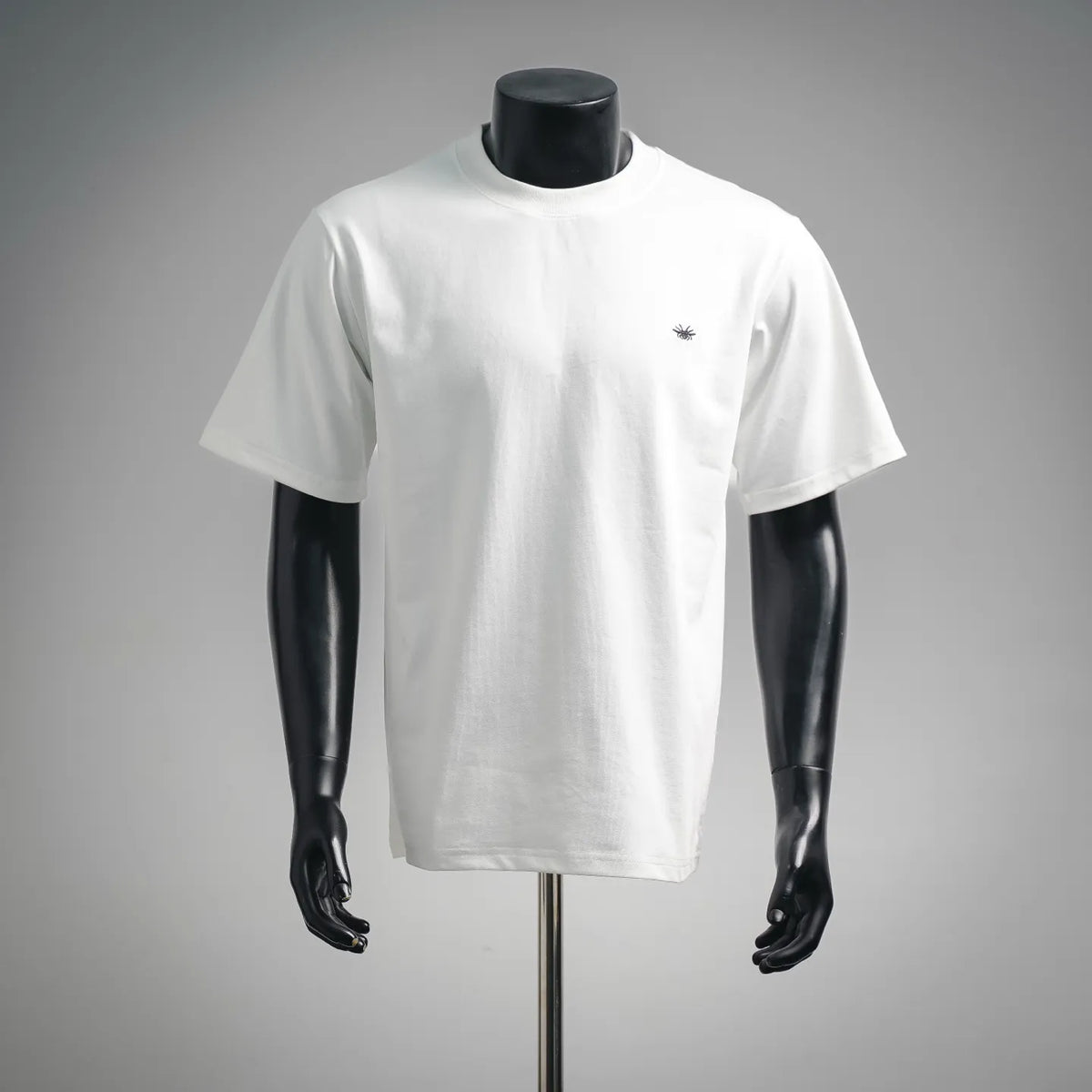 White short-sleeve T-shirt with small black embroidered emblem on the chest