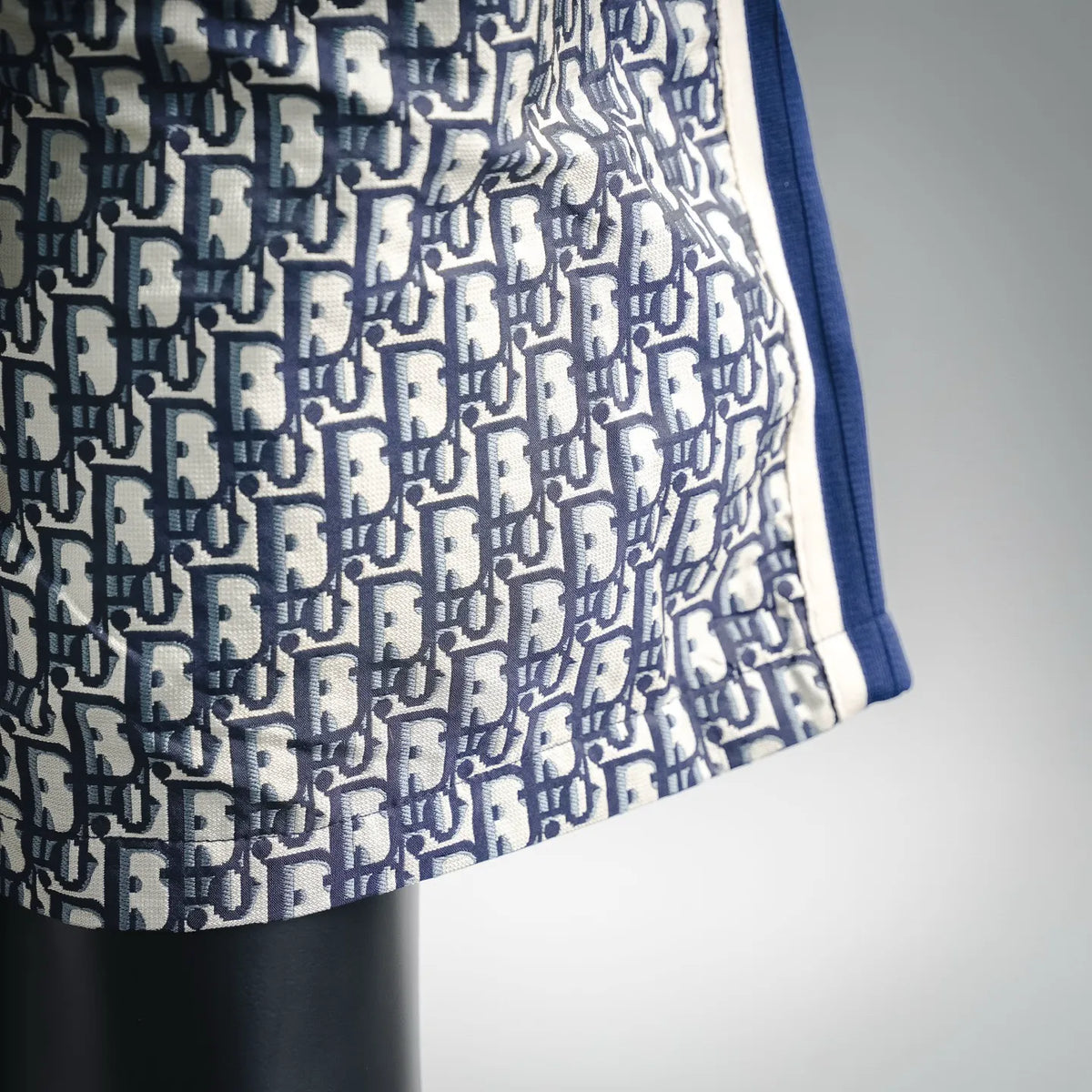 Dior shorts fabric close-up showing navy and cream logo pattern