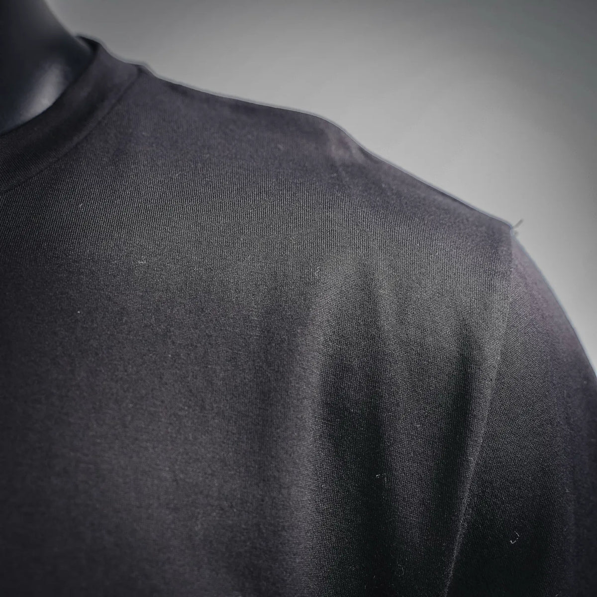 Dark T-shirt fabric close-up with smooth knit texture.