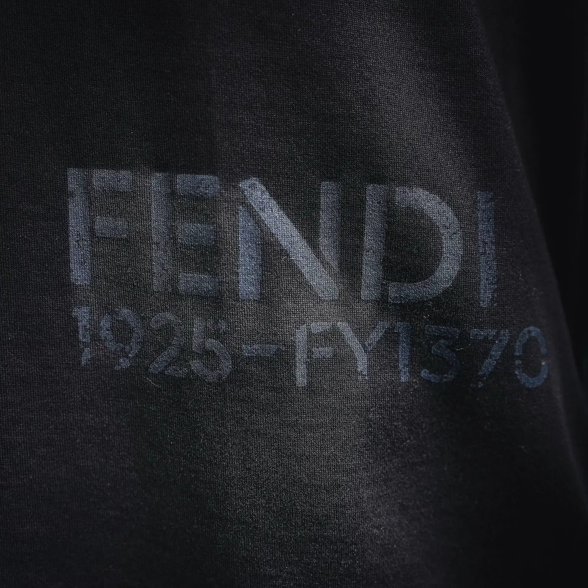 Dark T-shirt with FENDI graphic logo across the chest.