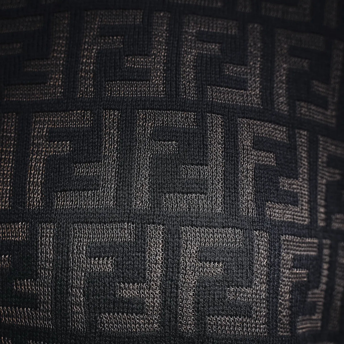Close-up of Fendi knit sweater FF logo pattern in dark with light woven texture