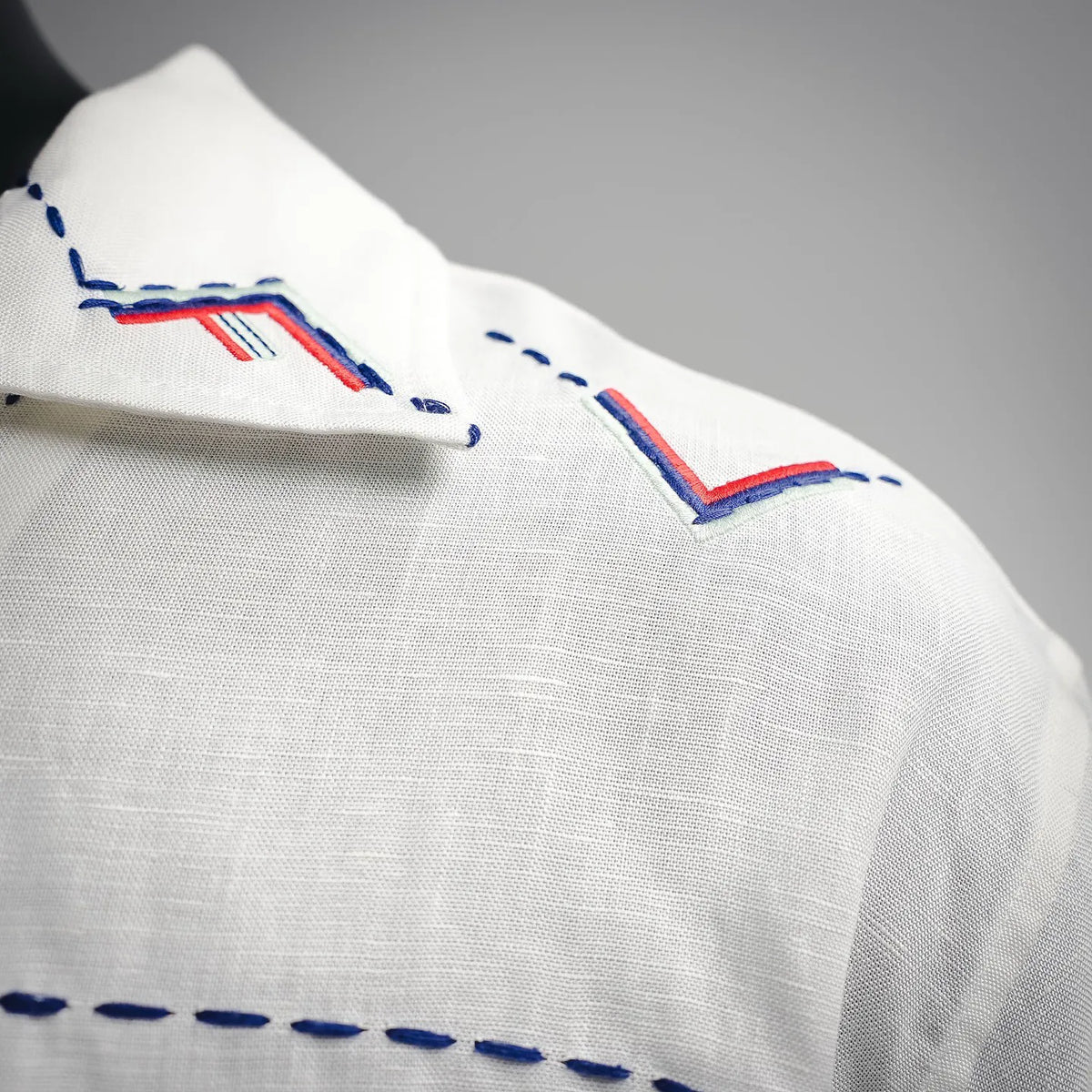 White shirt sleeve with blue-and-red embroidered graphic
