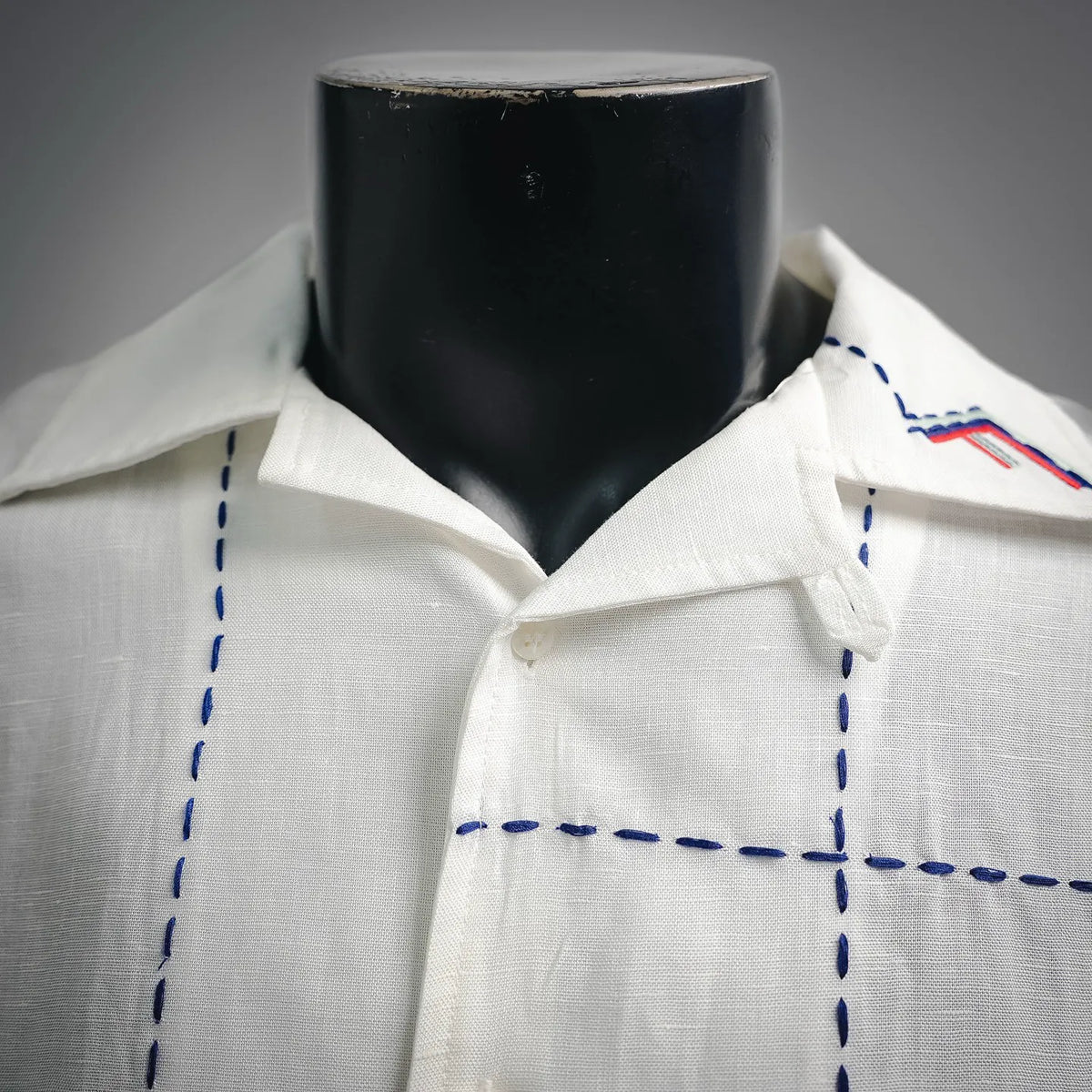 White shirt front with point collar, blue dashed stitching and embroidery