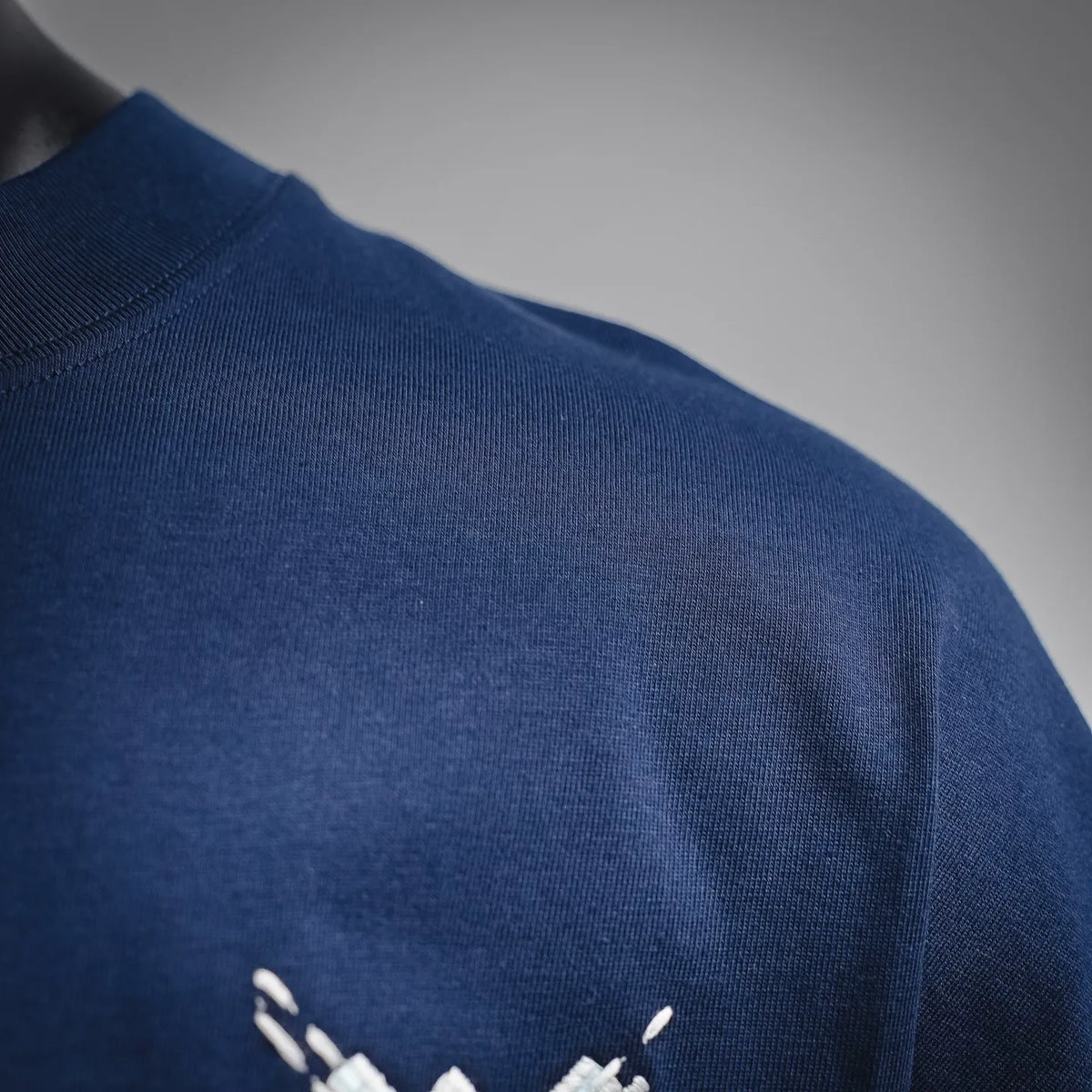 Blue T-shirt shoulder area with ribbed knit and white stitched seam