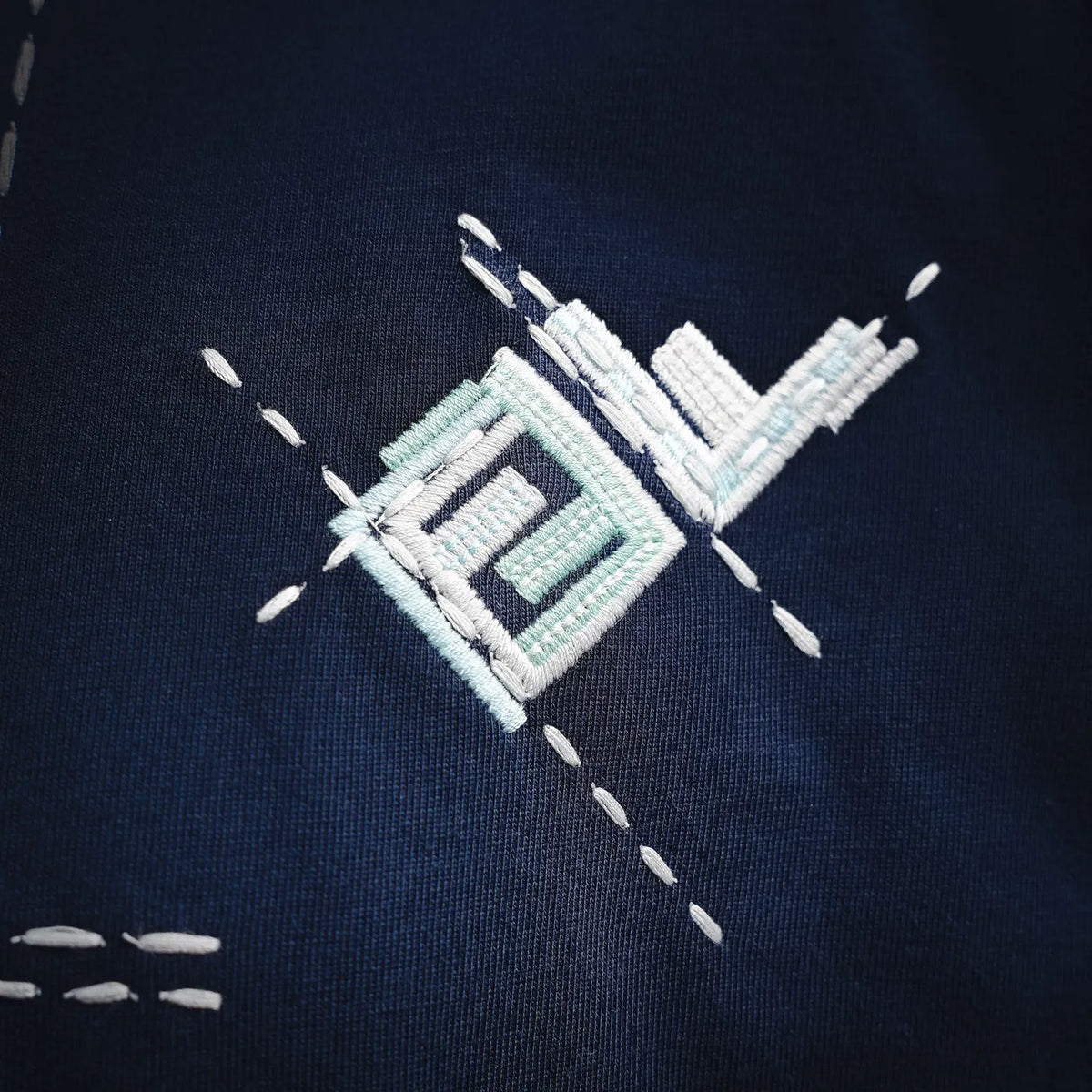 Blue T-shirt chest embroidery with geometric logo and dotted outline