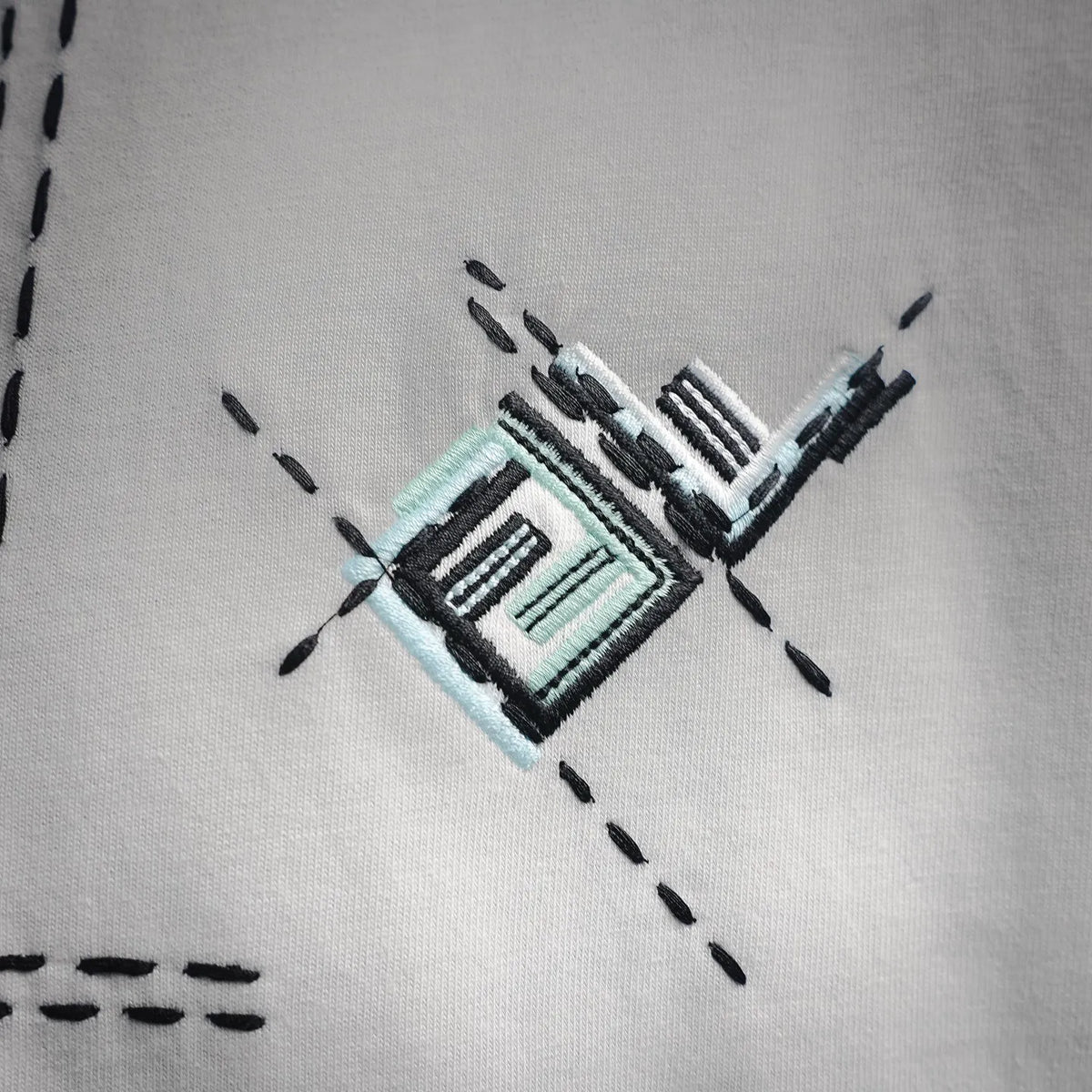 White T-shirt chest graphic patch with black dashed stitching and teal accent