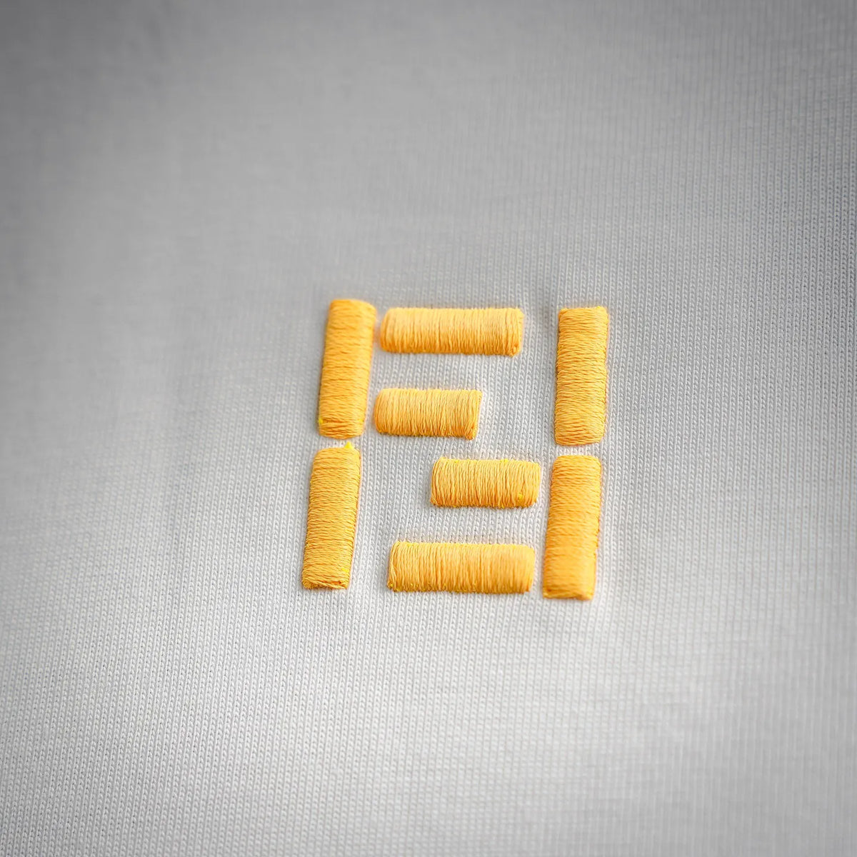 Yellow Fendi logo embroidery on white T-shirt fabric