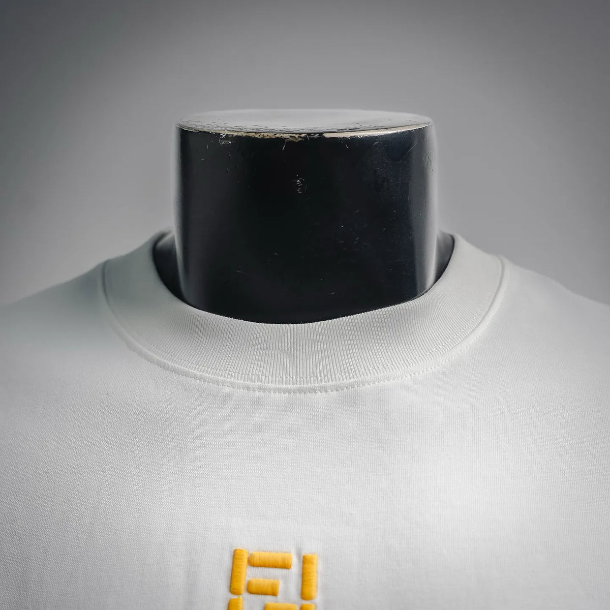 White crew-neck T-shirt with yellow embroidered logo on chest