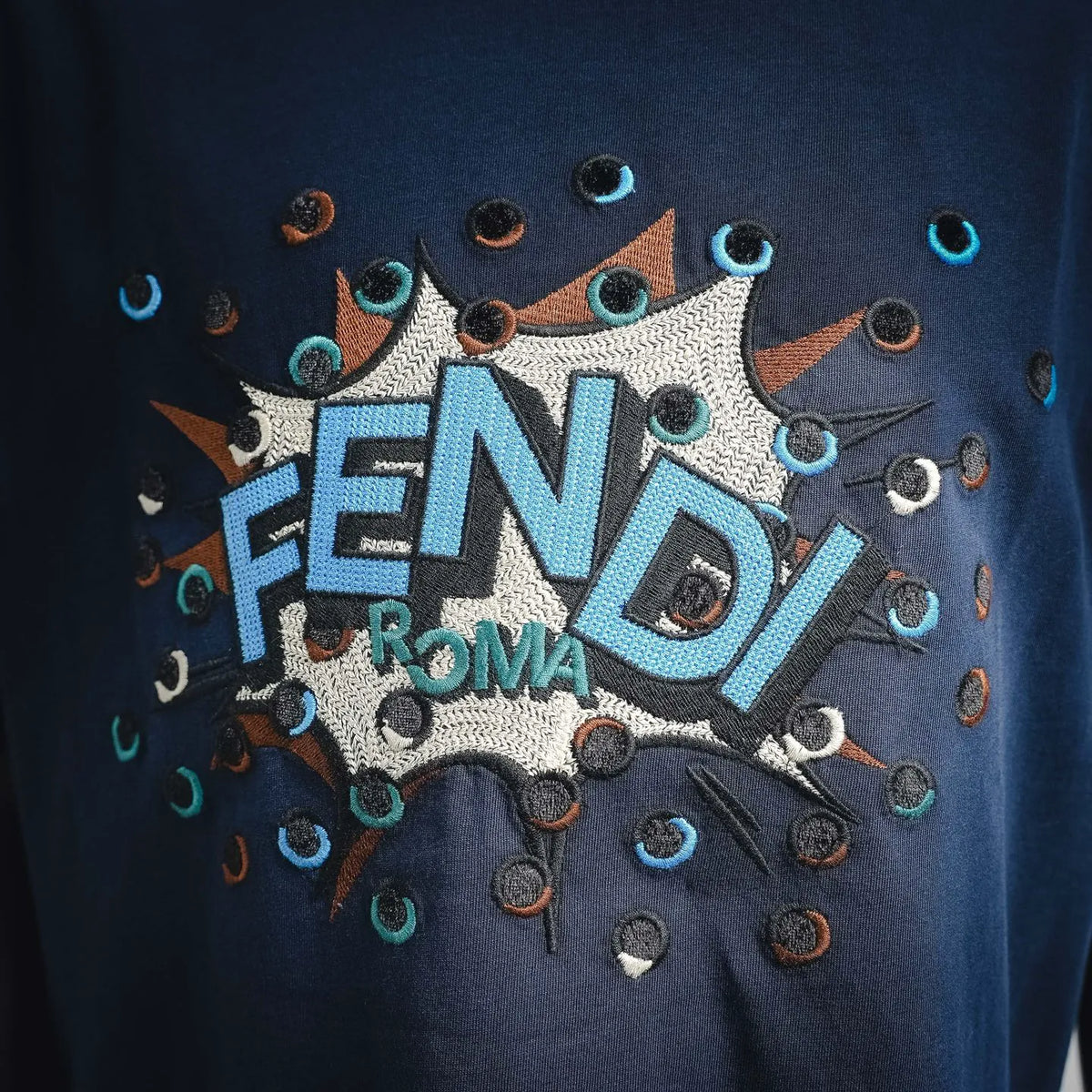 Fendi T-shirt front graphic close-up with FENDI ROMA text and decorative icons