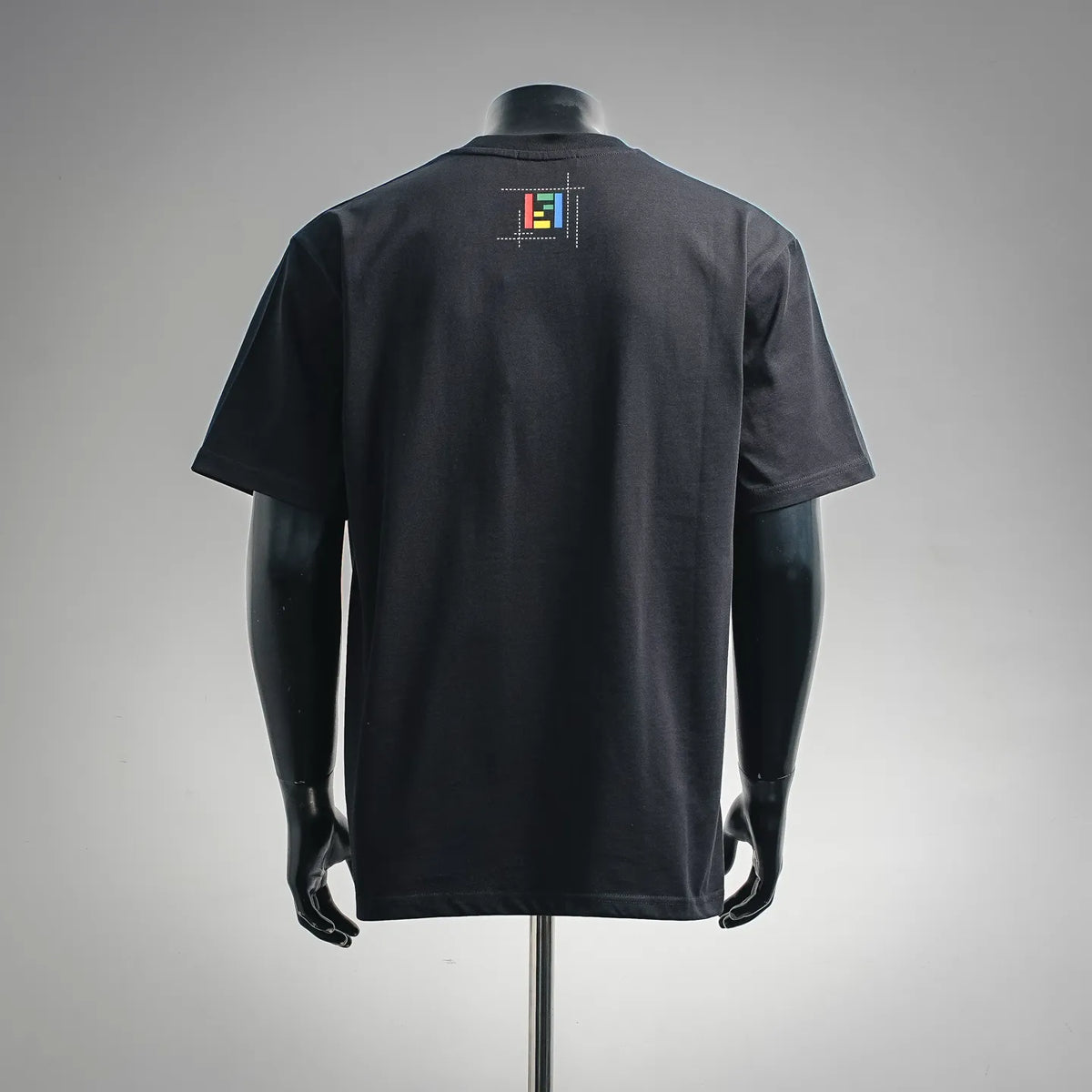 Black short-sleeve T-shirt with small Fendi logo patch graphic on back.