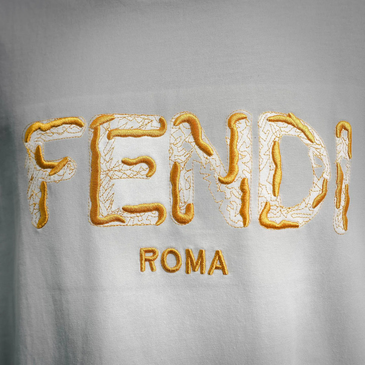 White Fendi short-sleeve T-shirt, close-up of gold embroidered FENDI ROMA text