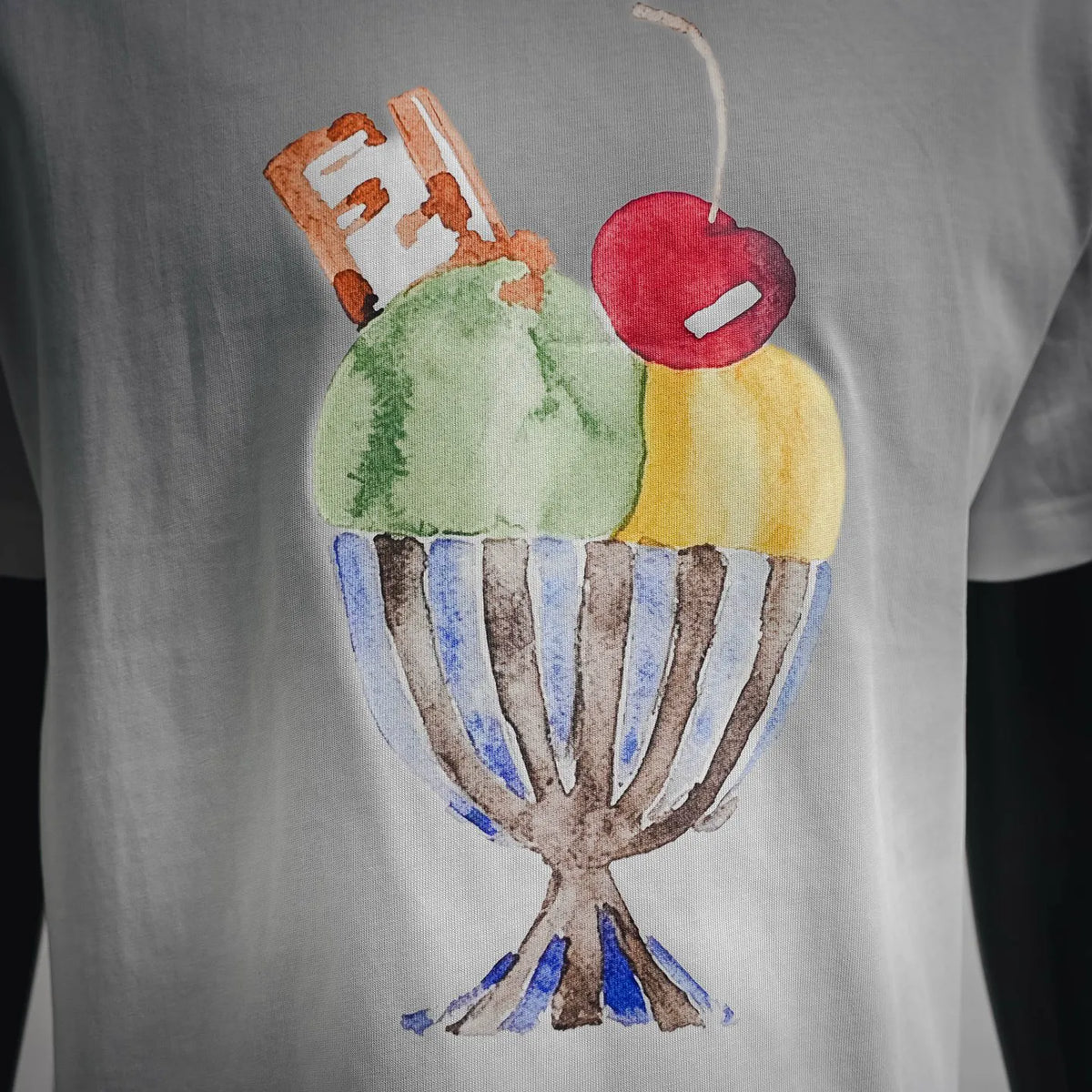 White T-shirt with colorful cupcake-style graphic print detail.