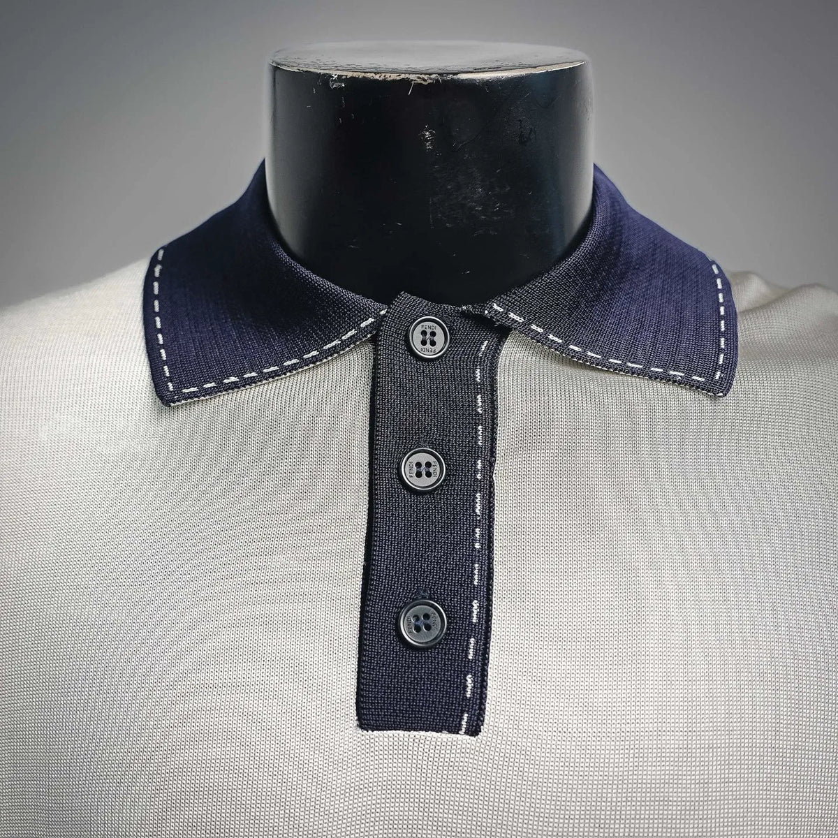 Fendi polo collar close-up: navy collar with white stitching and three dark buttons