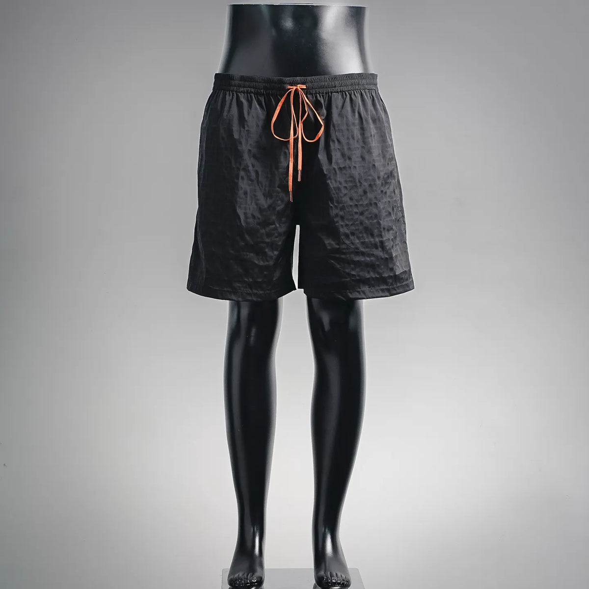 Black drawstring shorts on mannequin, front view with orange tie