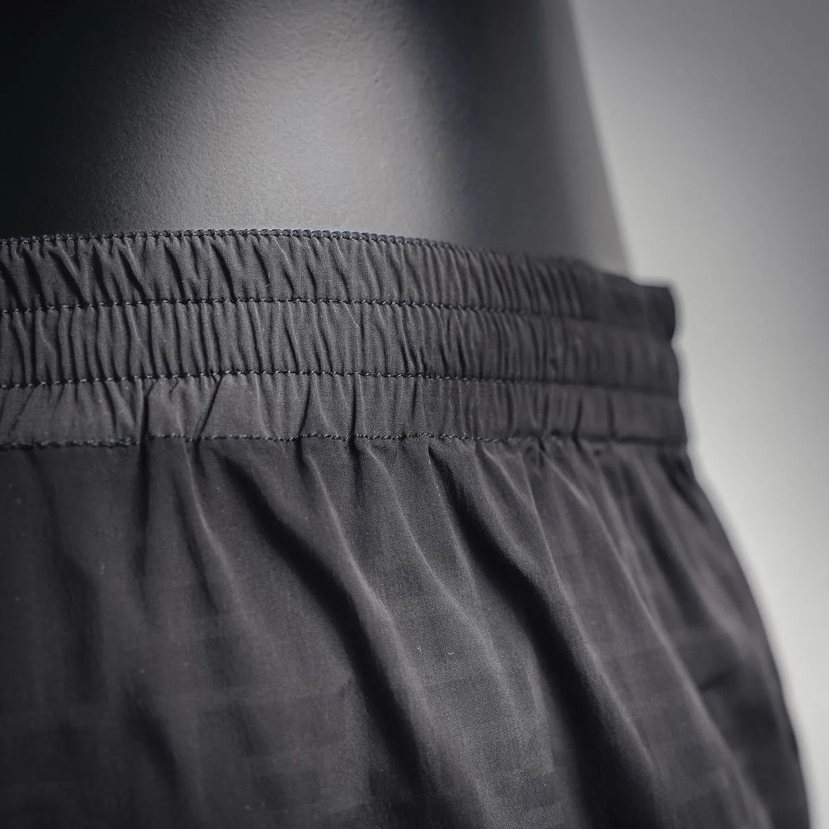 Black elastic-waist shorts fabric close-up with gathered waistband