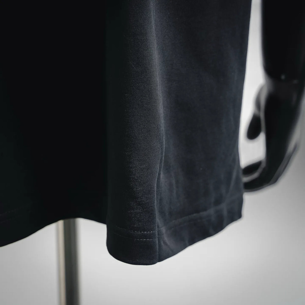 Black short-sleeve T-shirt hem with visible stitching detail