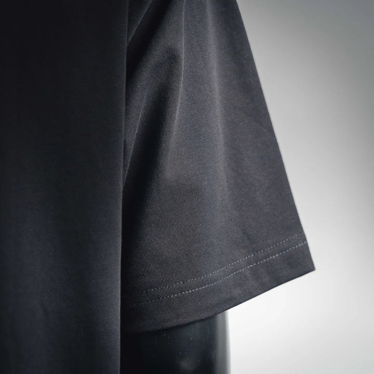 Dark short-sleeve T-shirt fabric with visible knit texture and stitched hem