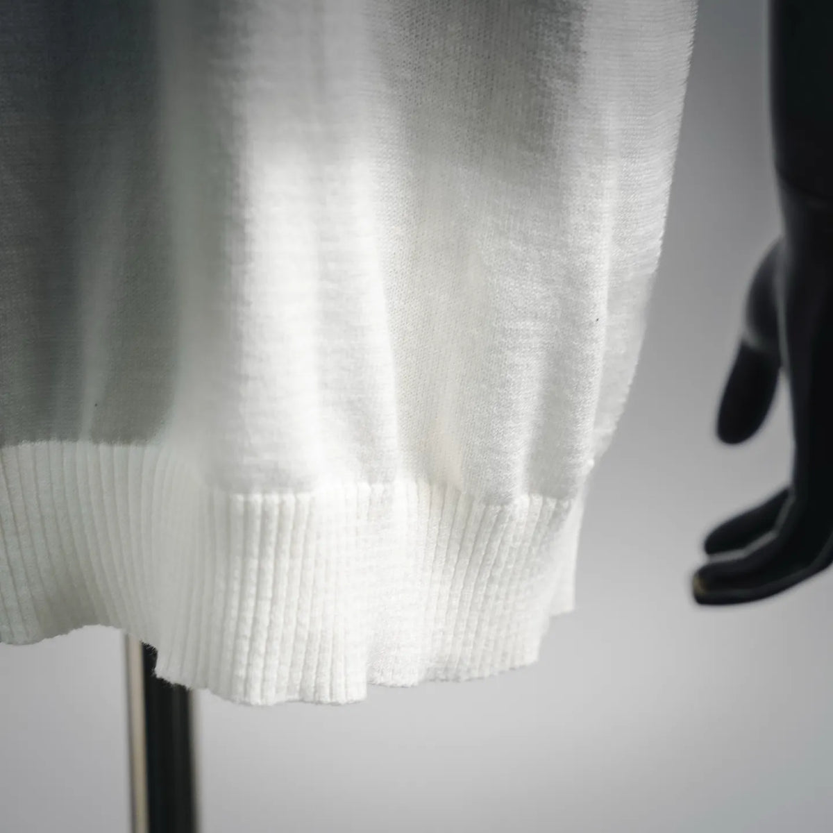 White knit sweater hem with ribbed cuff detail at the bottom edge
