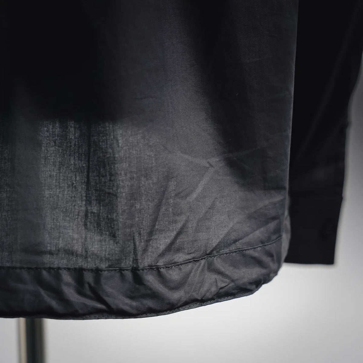 Black coat hem with slight drape and stitched edge detail