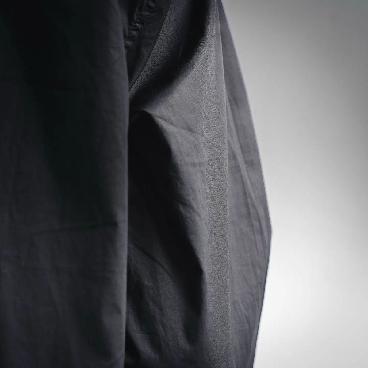 Black coat side panel with smooth fabric and vertical seam detail